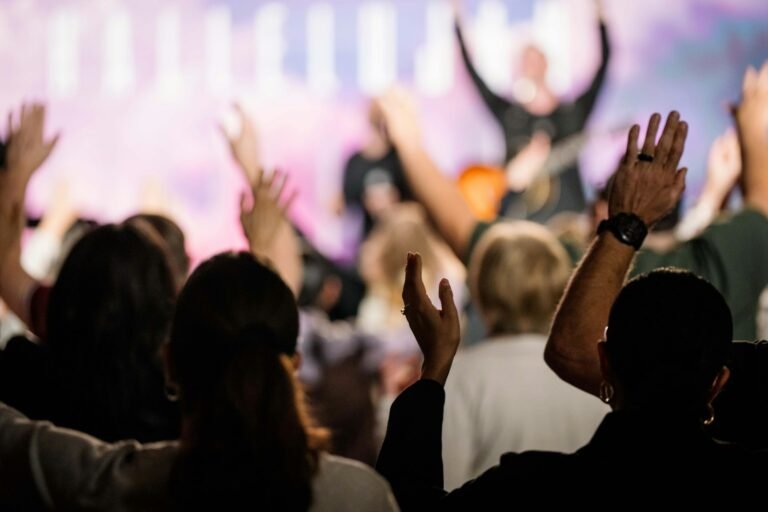 Congregação em momento de adoração em um culto cristão, com pessoas de mãos erguidas louvando a Deus