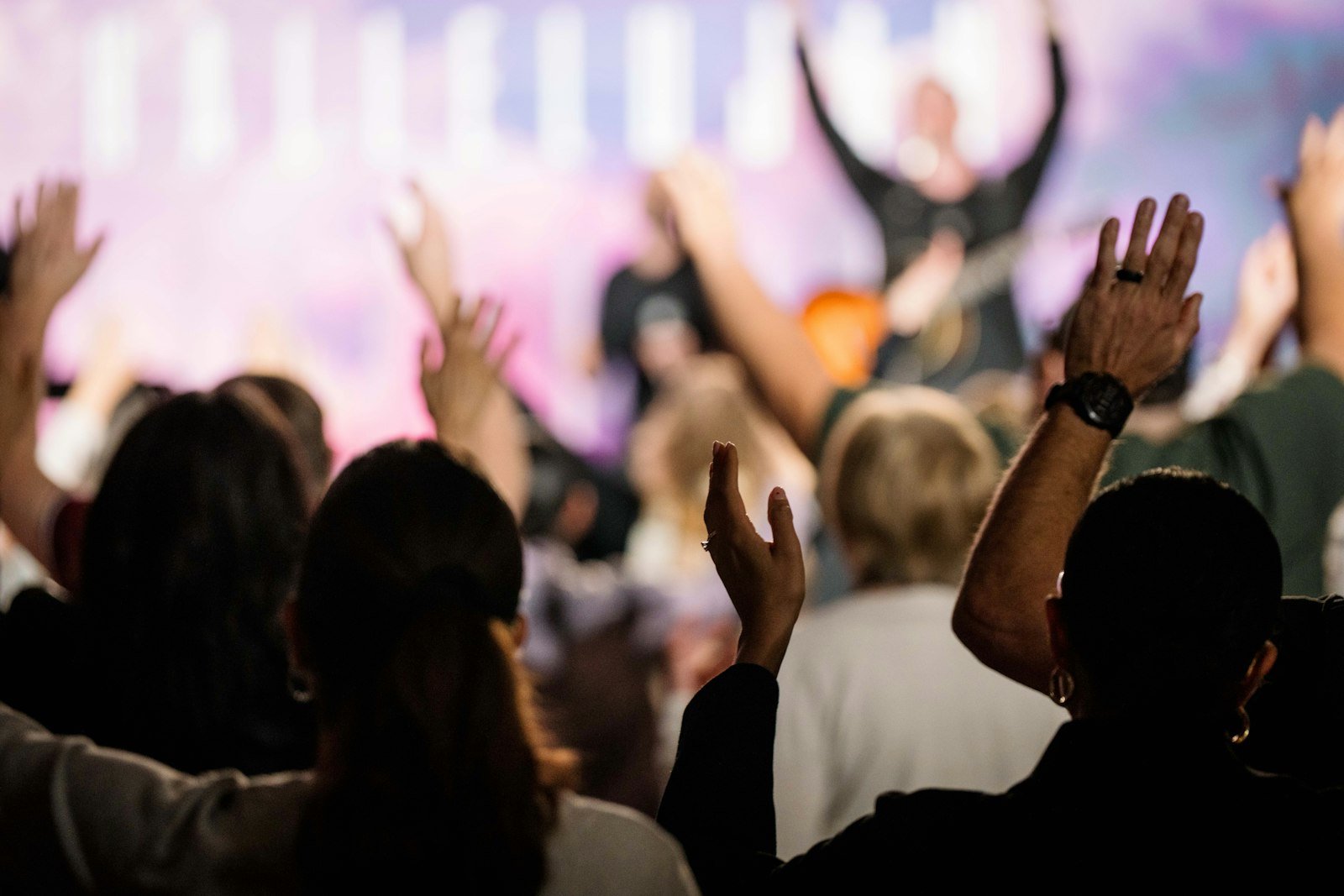 Congregação em momento de adoração em um culto cristão, com pessoas de mãos erguidas louvando a Deus