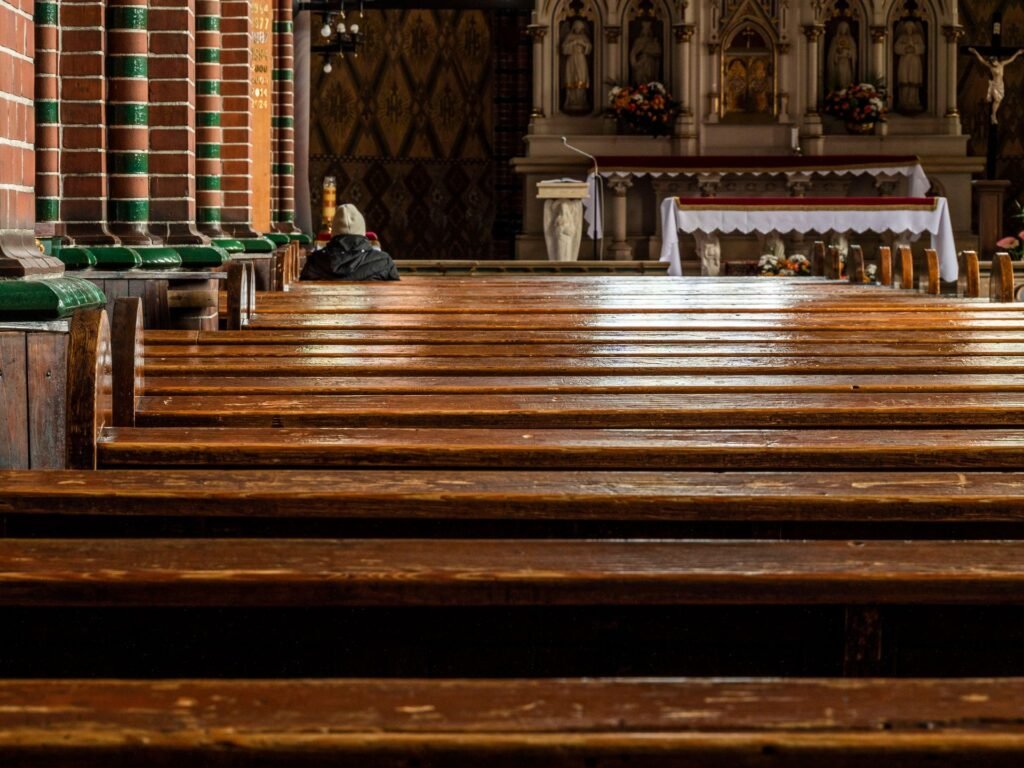 Burnout pastoral: pessoa orando sozinha em igreja com bancos de madeira e altar iluminado, símbolo de descanso espiritual