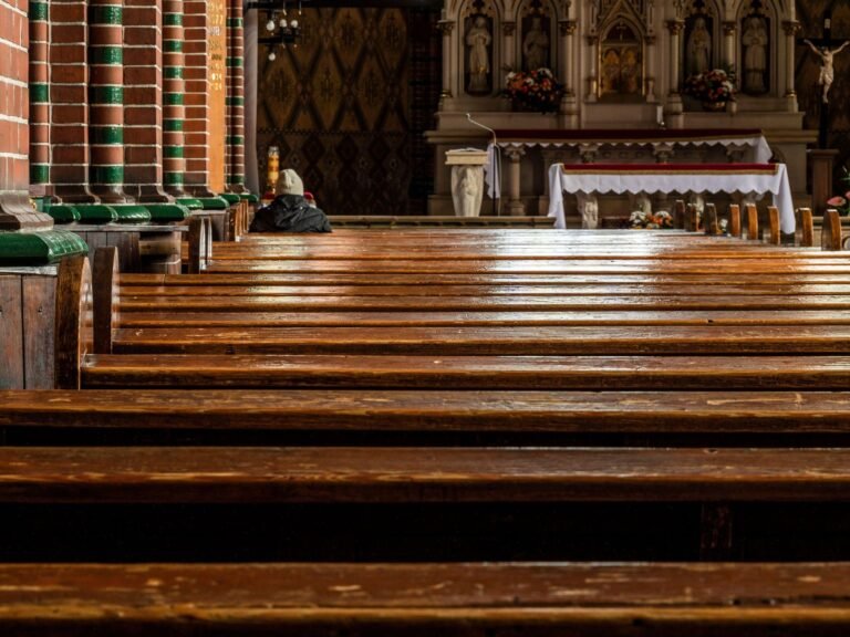 Burnout pastoral: pessoa orando sozinha em igreja com bancos de madeira e altar iluminado, símbolo de descanso espiritual